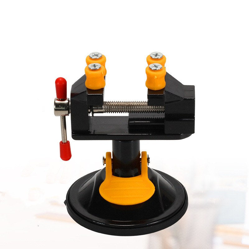 Black mini carving vise on a round suction cup base with a yellow locking lever and four orange jaw caps